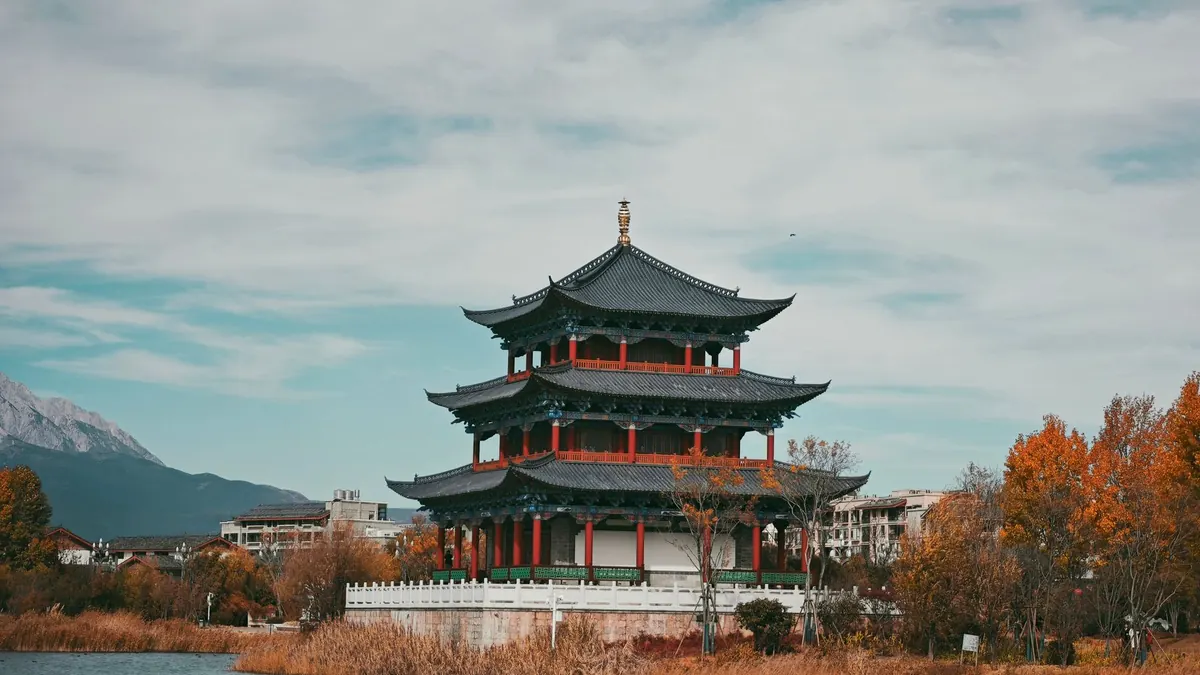 A traditional pavilion by autumn reeds, with Jade Dragon Snow Mountain beyond, in Lijiang